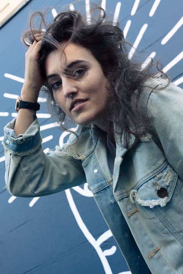 Portrait in a denim jacket against a blue painted mural
